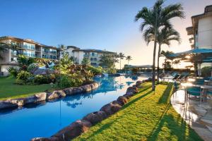 a resort swimming pool with palm trees and a resort at Waipouil Beach Resort Gorgeous Ocean Front Condo! Sleeps 8 AC Pool in Kapaa