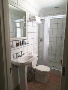 Un baño con inodoro, lavabo y espejo. en Zevenwacht Cottages, en Kuilsrivier