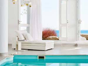 a living room with a white couch and a window at Mykonos Blu, A Grecotel Resort to Live in Psarou