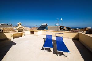 two blue chairs on a roof with the ocean in the background at Sicilia Case Vacanze in Balestrate
