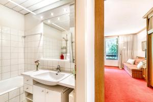 een witte badkamer met een wastafel, een bad en een bank bij Appartment Studio Zentral by A-Appartments in Brand