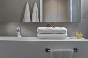 ein Bad mit einem Waschbecken, Handtüchern und einem Spiegel in der Unterkunft Nissi Beach Resort in Ayia Napa