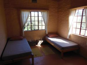 2 camas en una habitación con 2 ventanas en Simonskloof Mountain Retreat, en Montagu