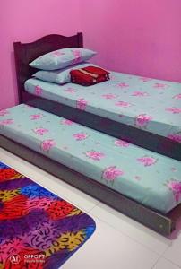 two beds in a room with pink walls at Nurul Homestay in Kepala Batas