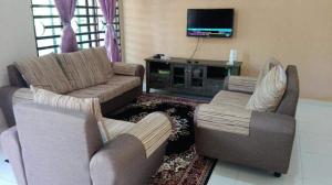 Nurul Homestay في كيبالا باتاس: غرفة معيشة مع كنبتين وتلفزيون