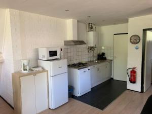 eine Küche mit weißen Geräten und einer weißen Mikrowelle in der Unterkunft Vosseven 79 Melkeppe in Stramproy