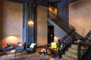 a lobby with a staircase with chairs and tables at Continental Hotel in Reims