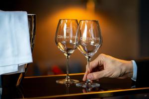 a person holding two wine glasses on a table at Continental Hotel in Reims