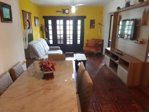 a living room with a large wooden table and yellow walls at apartamento a 20 metros do mar bombinhas in Bombinhas