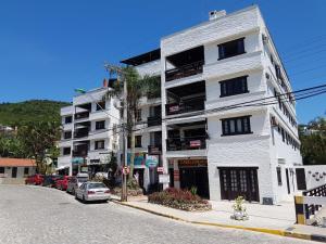 a white building on the side of a street at apartamento a 20 metros do mar bombinhas in Bombinhas