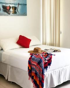 a bed with a hat and a blanket on it at Pousada Bella Boipeba in Ilha de Boipeba