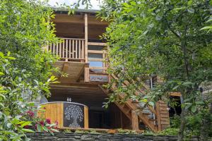a tree house with a wooden staircase and a balcony at Amelu' in Ostana