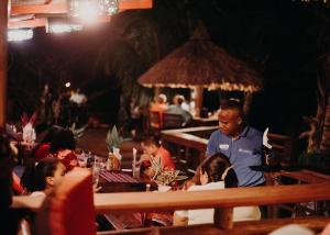 a man standing in a restaurant with people sitting at tables at Tranquilseas Eco Lodge & Dive Center in Sandy Bay