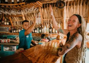 two people standing at a bar with their hands in the air at Tranquilseas Eco Lodge & Dive Center in Sandy Bay
