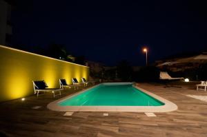 a swimming pool at night with chairs around it at La Dimora Del Bue in Matera