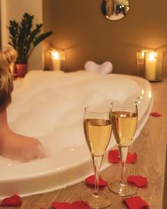 two glasses of champagne sitting next to a bath tub at Domaine de Bellevue, The Originals Relais (Relais du Silence) in Neufmoutiers-en-Brie