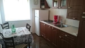eine Küche mit Tisch, Spüle und Kühlschrank in der Unterkunft Apartman Marin in Šilo