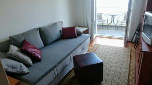 ein Wohnzimmer mit einem blauen Sofa mit roten Kissen in der Unterkunft Apartman Marin in Šilo