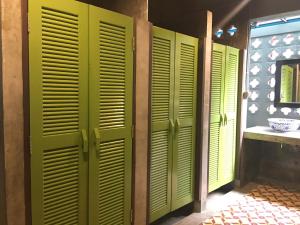 a row of green wooden doors in a bathroom at Talardkao Balcony Krabi in Krabi town