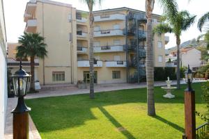 a building with palm trees in front of a yard at Castelvetere Hotel in Caulonia