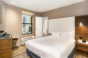 a bedroom with a large white bed and a window at The Gallivant Times Square in New York