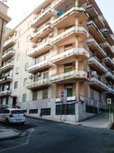 un gran edificio de apartamentos con un coche aparcado delante de él en Appartamento Signorile AMBIENTI SANIFICATI, en Messina