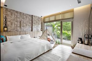 una camera da letto con un letto bianco e una grande finestra di JBG Hotspring Resort Hotel a Taipei