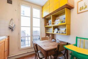 eine Küche mit einem Holztisch und einem Fenster in der Unterkunft séjour Haut Marais in Paris