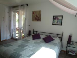 Un dormitorio con una cama con almohadas moradas. en Le Verger du Sausset en Beaune