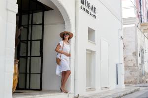 a woman in a white dress and hat standing outside a building at Musae Relais & SPA in Polignano a Mare