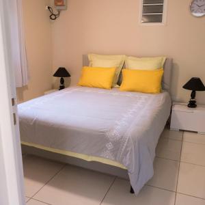 um quarto com uma cama com almofadas amarelas em Chez Francis em Petit-Bourg
