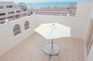 una silla con sombrilla en el balcón en Arees Beach, en Rayyis