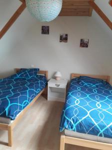 1 dormitorio con 2 camas y edredón azul en maison d'a coté, en Garlan