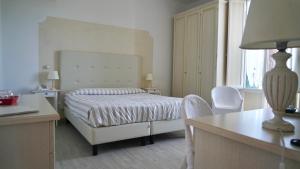 a hotel room with a bed, chair, and a mirror at Hotel La Primula in Forte dei Marmi
