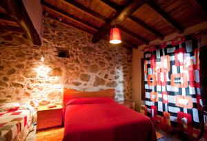 a bedroom with a red bed and a stone wall at Las Mimbres in Fuentes de Béjar