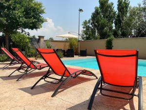 a row of chairs sitting next to a swimming pool at La Maison de Caillette in Camaret-sur-Aigues