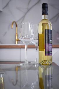 eine Flasche Wein neben zwei Weingläsern in der Unterkunft VOYA Apartments - a luxury oasis in the old town in Braşov