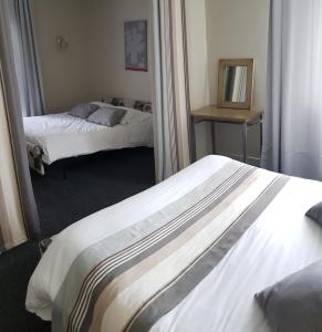 two beds in a hotel room with a mirror at Hotel Pyrenées Atlantique in Saint-Pée-sur-Nivelle