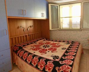 a bedroom with a bed with a red and white blanket at Holiday House Monte Longu in Posada