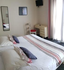 1 dormitorio con cama blanca con almohadas y escritorio en Hotel Pyrenées Atlantique, en Saint-Pée-sur-Nivelle