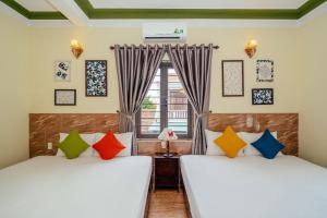 two beds in a room with a window at Green Bud hostel and homestay in Hoi An