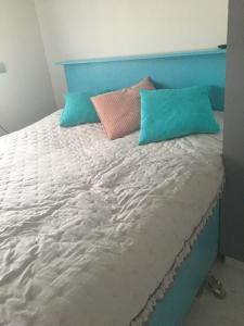 ein Bett mit blauen und rosa Kissen darauf in der Unterkunft Apartament DeLux in Rewal