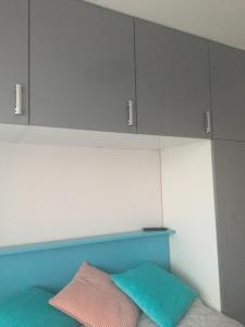 ein Bett mit blauen und grauen Schränken und einem Kissen in der Unterkunft Apartament DeLux in Rewal