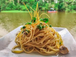a plate of spaghetti with green onions and mushrooms at Amazon Muyuna Lodge - All Inclusive in Paraíso +139 photos