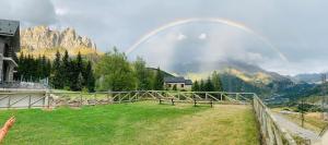 um arco-íris sobre um campo com uma casa e montanhas em Apartamentos Formigal - Admite mascotas - em Formigal