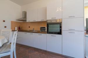 a kitchen with white cabinets and a microwave at Villa M in Crikvenica