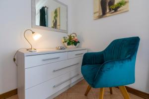 a bedroom with a blue chair next to a dresser at Villa M in Crikvenica
