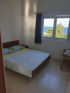 een slaapkamer met een bed en een raam bij Apartmani Mlikotić in Dugi Rat