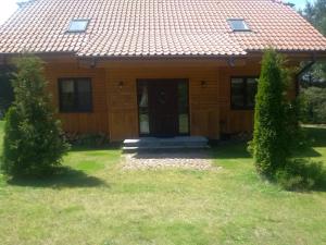 una casa de madera con una puerta y dos árboles en Za piecem en Guzowy Piec