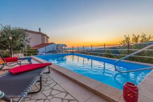 a swimming pool with a sunset in the background at Villa M in Crikvenica